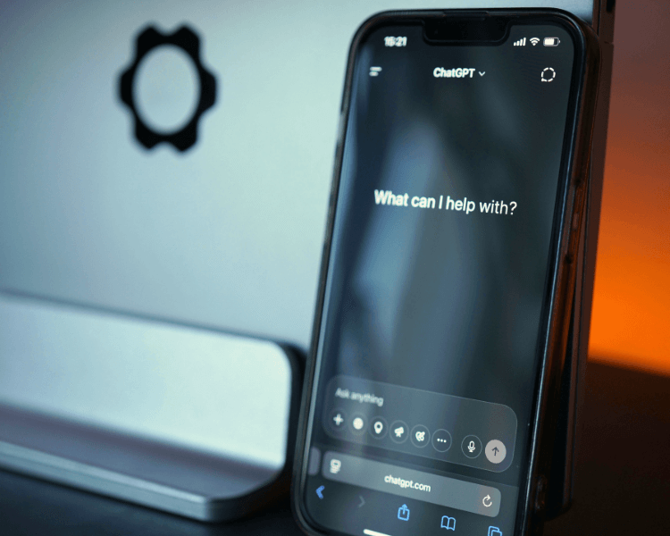 Smartphone displaying the ChatGPT interface in front of a computer monitor, representing AI-powered search and business discovery.