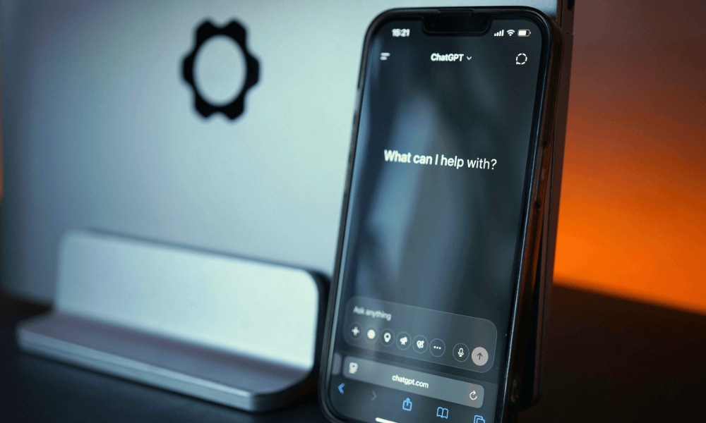 Smartphone displaying the ChatGPT interface in front of a computer monitor, representing AI-powered search and business discovery.